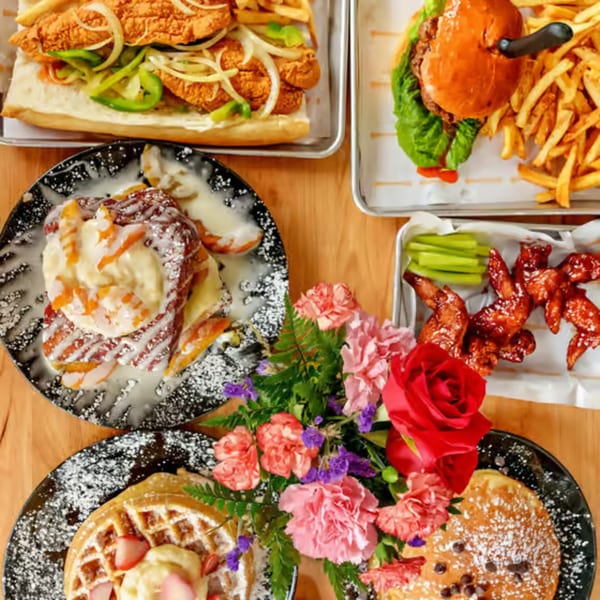 A table spread of Sunrise Social breakfast and lunch items, including waffles, pancakes, and sandwiches.