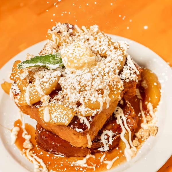 Sunrise Social's French toast with powdered sugar, apple topping, and a mint garnish.